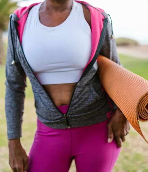 Smiling woman stretching gently outdoors in a park.